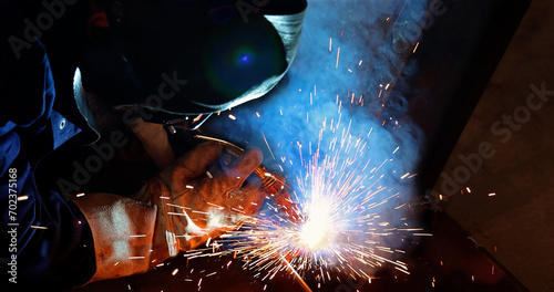 Welder at work in metal industry, welding metal construction. Close-up shot lots of sparks in the factory photo