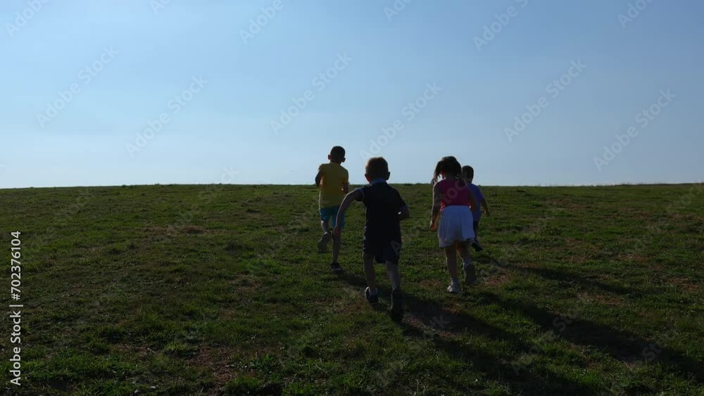 Three Boys and a Girl Run Across the Meadow Towards the Horizon on a Sunny Day Three Boys and a Girl Run Across the Meadow Towards the Horizon on a Sunny Day