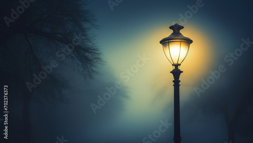 Mystical foggy night with glowing street lamp and silhouette of a leafless tree. Copy space photo