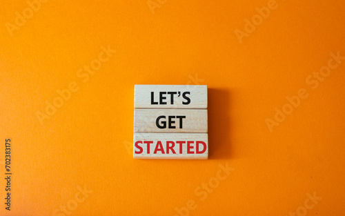 Lets get started symbol. Concept words Lets get started on wooden blocks. Beautiful orange background. Business and Lets get started concept. Copy space.