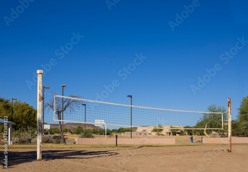 Volleyball net stretching above sandy ground of play court in a public Dos Lagos park, Glendale, Arizona