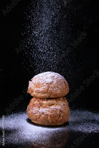 two Shu cakes and powdered sugar on a dark background