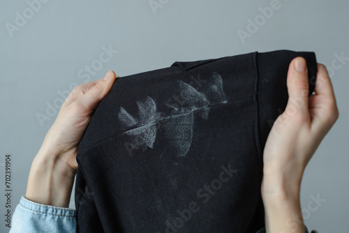 Deodorant stains on black clothes. Women's hands holding spoiled clothes. daily life stain concept. 