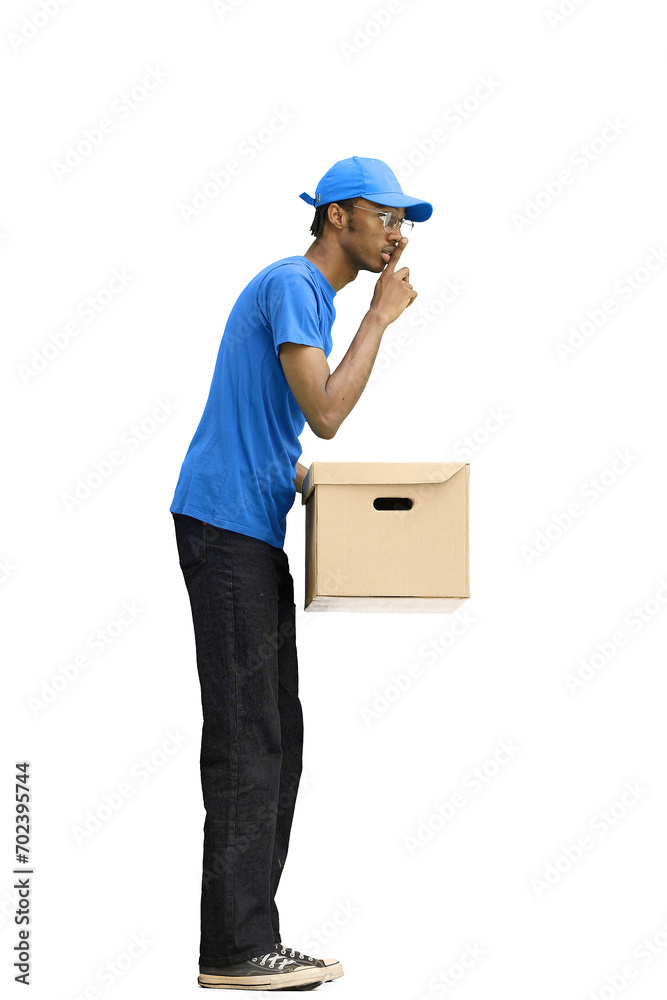 A male deliveryman, on a white background, in full height, with a box, shows a sign of silence A male deliveryman, on a white background, in full height, with a box, shows a sign of silence