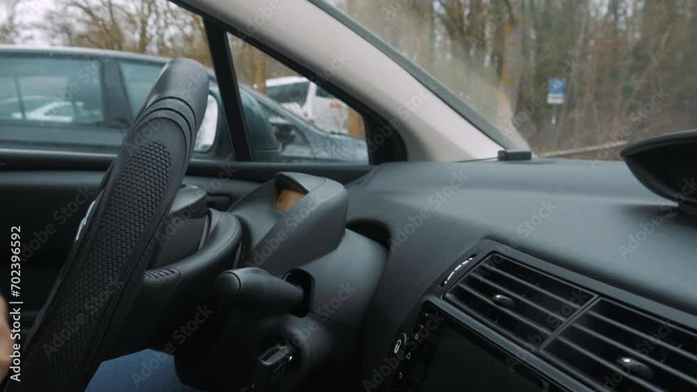 A disabled person parks a car while turning the steering wheel. The car stops. A disabled person parks a car while turning the steering wheel. The car stops.