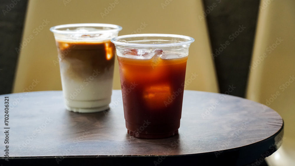 iced latte and ice americano coffee on a wooden table, Summer drinks background. Iced drink and iced coffee in to go glass. Coffee shop or cafe and restaurant. iced latte and ice americano coffee on a wooden table, Summer drinks background. Iced drink and iced coffee in to go glass. Coffee shop or cafe and restaurant.