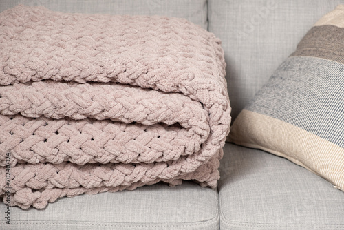 Knitted large plaid blanket in dusty rose light grayish-red color on the sofa. photo