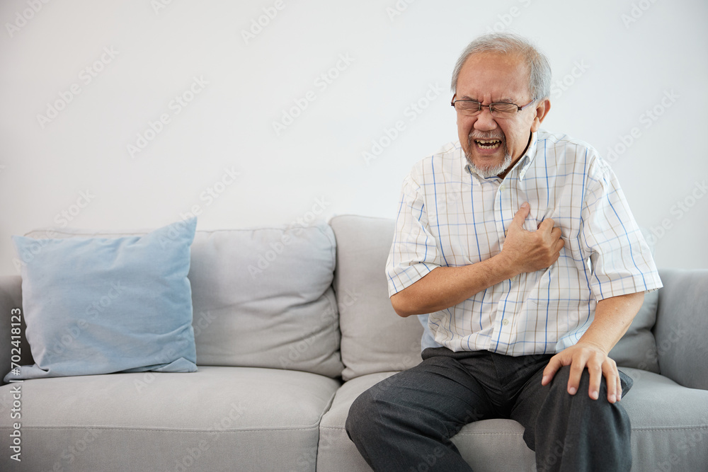 senior elderly man have a chest pain or suffering from heart attack on a sofa