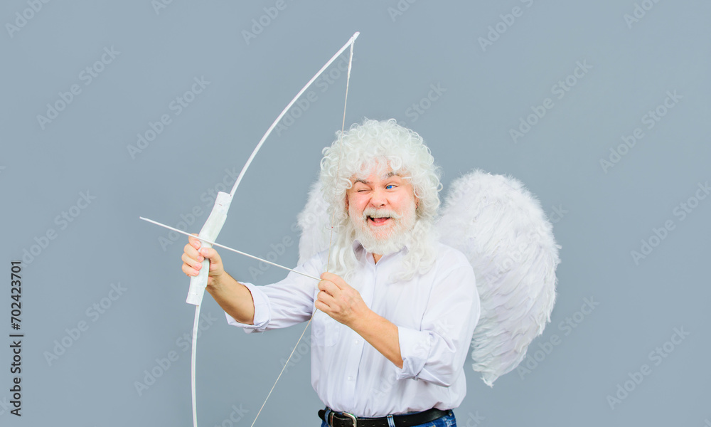 Valentines Day celebration. Happy bearded man in angel wings with bow and arrow. God of love. Valentine cupid in white wig shooting with bow. Arrow of love. February 14. Male angel with bow and arrow. Valentines Day celebration. Happy bearded man in angel wings with bow and arrow. God of love. Valentine cupid in white wig shooting with bow. Arrow of love. February 14. Male angel with bow and arrow.