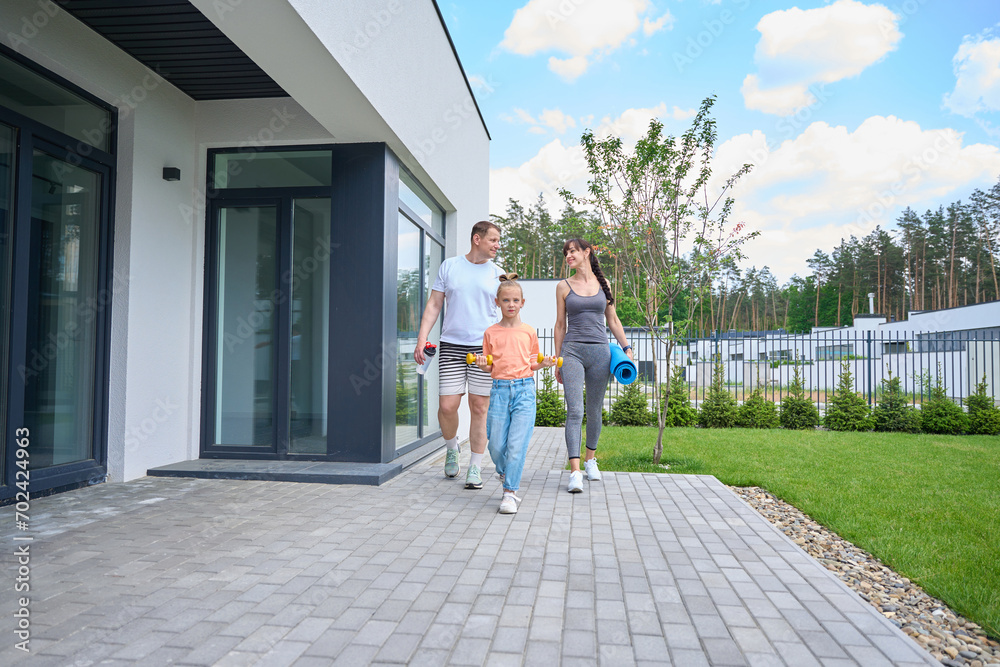 Caucasian family walking on terrace near townhouse before workout outdoors Caucasian family walking on terrace near townhouse before workout outdoors