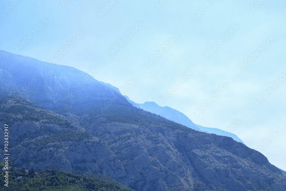 Background of mountains in blue fog. Silhouette of mountains. Tourism. Outdoor activity in the nature. Beautiful landscape. Croatia. Vacation and summer concept. Mountain landscape