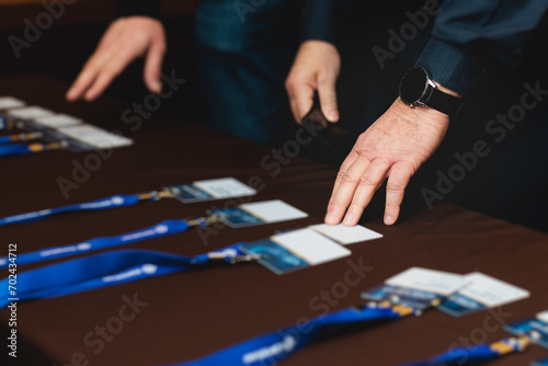 Process of checking in on a conference congress forum event, registration desk table, visitors and attendees receiving a name badge and entrance wristband bracelet and register electronic ticket photo