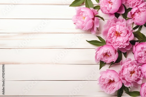 Flat lay of pink peony flowers with copyspace on wooden background © Alina
