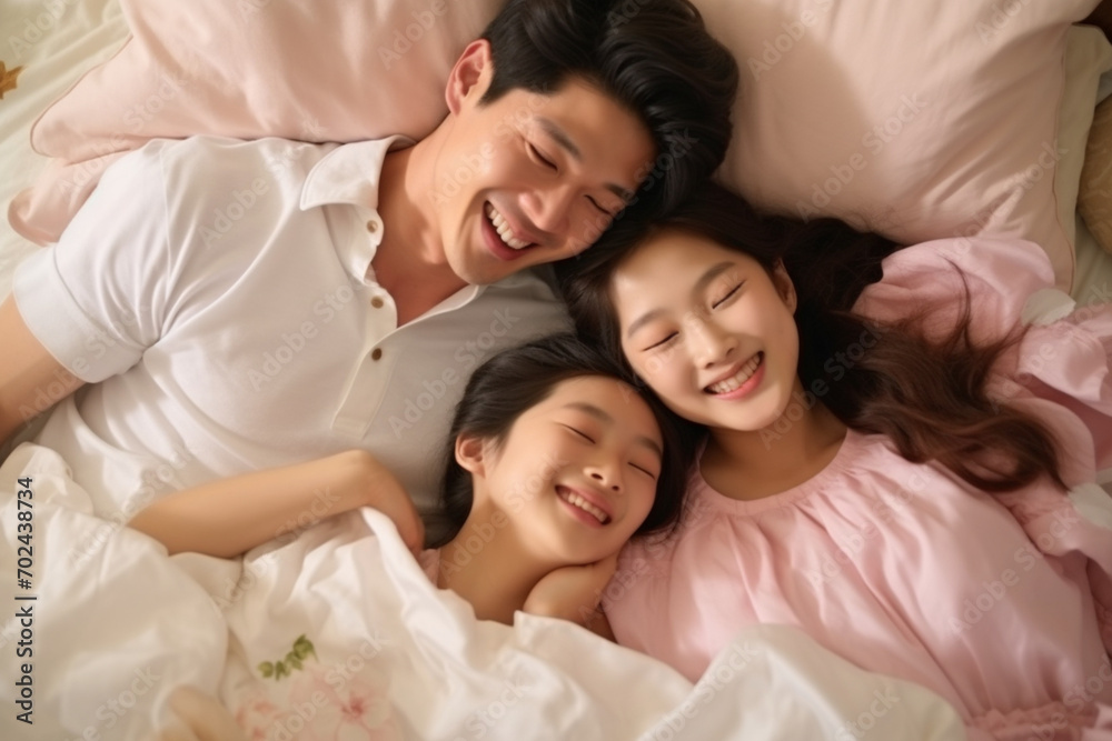Happy Asian family lying on bed in bedroom with happy and smile, top view