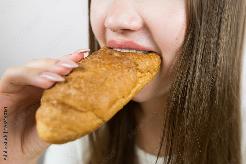 young beautiful girl eating a croissant, close-up, crop photo. female mouth eating croissant young beautiful girl eating a croissant, close-up, crop photo. female mouth eating croissant