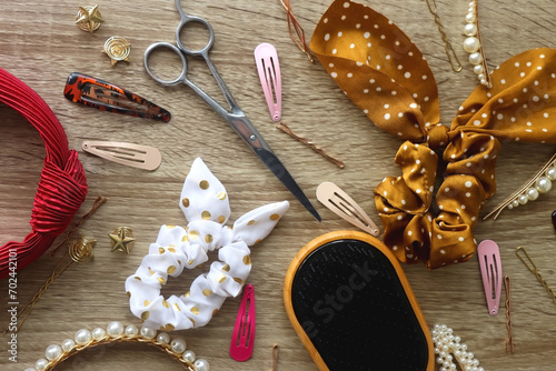 Wooden hairbrush, scissors and various headbands, hair clips and scrunchies on wooden background. Flat lay. photo