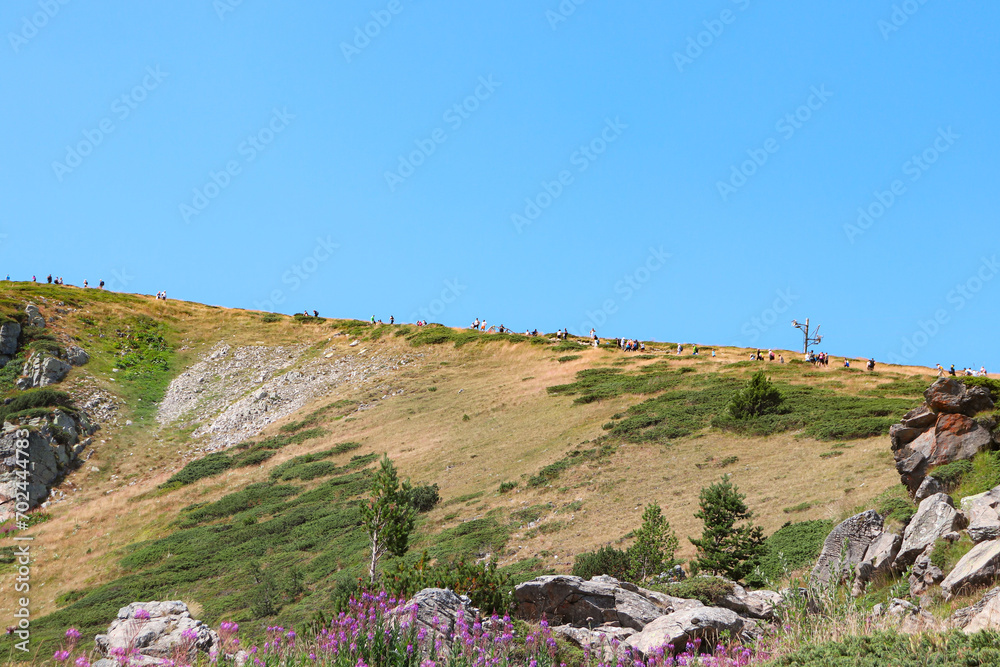 Hiking tourists walking along the red trail at Seven Rila Lakes national park during the summer season Hiking tourists walking along the red trail at Seven Rila Lakes national park during the summer season