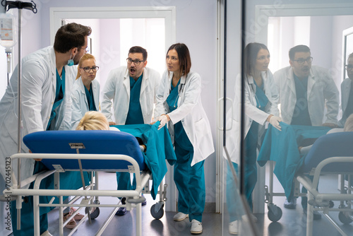 Discussion between medical team while pushing patient into operating room. Surgeons running out of time, wheeling patient into operating theatre.
