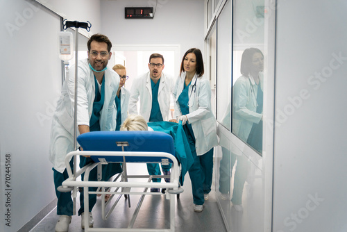 Professional team of surgeon  doctors and nurse moving injured patient on a gurney to the emergency operating room. Medical team pushing patient on the bed into urgent surgery at the hospital.