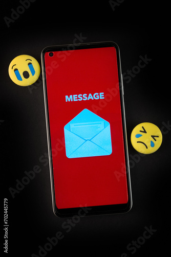 Emoji face and smartphone on black background. Emoticon concept. photo