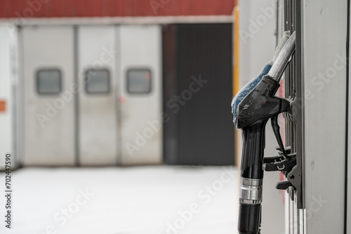 Gas pump handles at a gas station in winter.