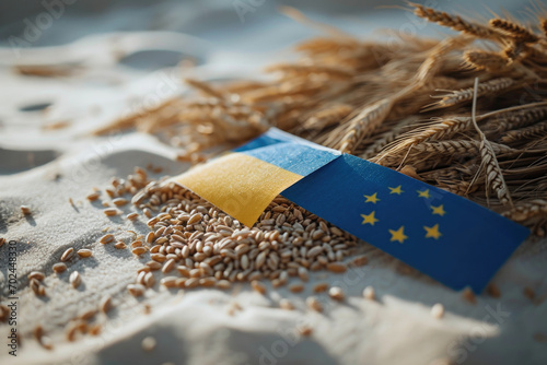 Wheat grains scattered on a white surface with flags. The Ukrainian flag on the left and the European Union flag on the right suggest an agricultural partnership photo