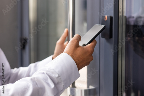 Hand man closely with the phone, the businessman uses the application on the smartphone to remove the door opening of the house, office.