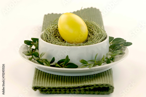 Yellow Easter egg lying on grass in bowl photo