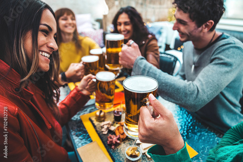 Group of happy friends drinking and clinking beer glasses at brewery bar restaurant - Cheerful millenial people having dinner party sitting in pub garden - Food, beverage and friendship concept photo