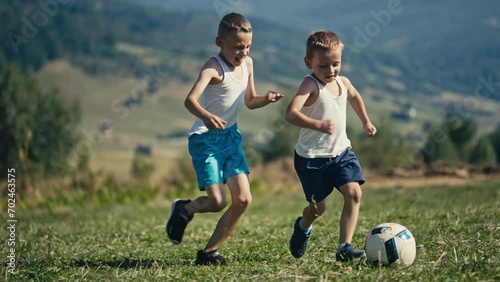Older Brother Knocks Younger on the Grass During a Football Play in Nature photo