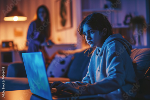 Teenage girl sitting with laptop computer at home and ignoring her frustrated mother. Online video games addiction, learning difficulties, social networks, cyber security,entertainment for teens photo