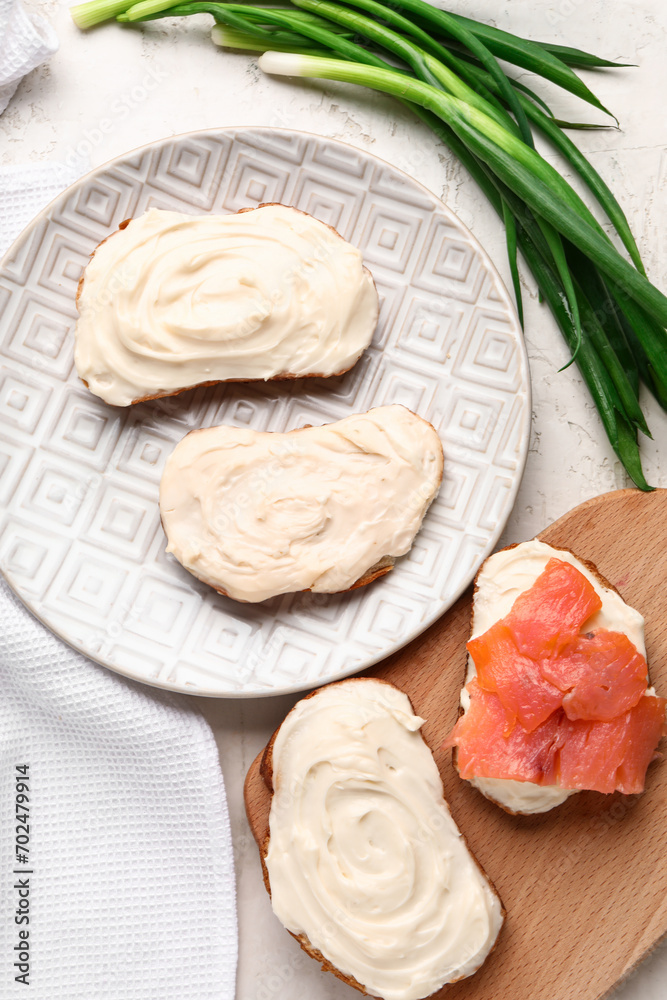 Tasty sandwiches with cream cheese and fish on light background