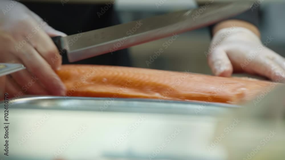 Chef is slicing multiple pieces of the salmon with a sharp knife. Chef is is preparing the salmon pieces with a kitchen knife. Chef makes salmon sashimi pieces with the knife. Japanese Food Cafe Chef is slicing multiple pieces of the salmon with a sharp knife. Chef is is preparing the salmon pieces with a kitchen knife. Chef makes salmon sashimi pieces with the knife. Japanese Food Cafe