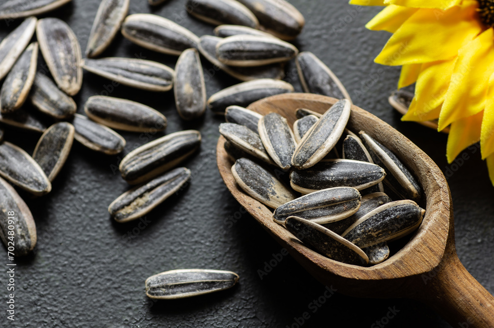 Pile of black roasted salty sunflower seeds with flower on rustic table, nut concept, Helianthus annuus Pile of black roasted salty sunflower seeds with flower on rustic table, nut concept, Helianthus annuus