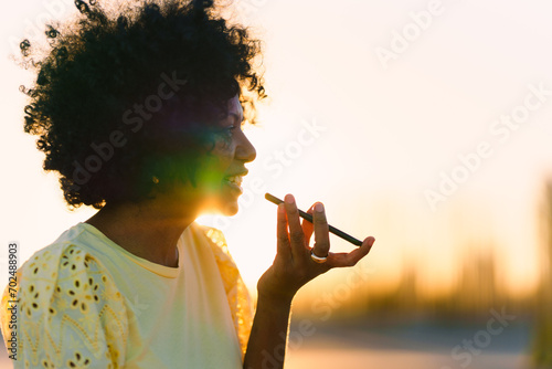 Rays of the sun illuminating an african woman sending a voice message © Egoitz