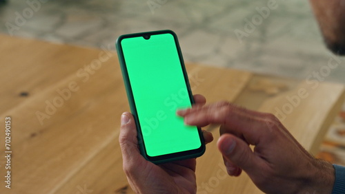 User scrolling chromakey smartphone at cabinet closeup. Man hand holding device