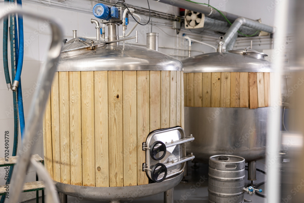 Φωτογραφία Interior of small private brewery with steel tanks trimmed with wooden planks for beer fermentation and kegs for storaging