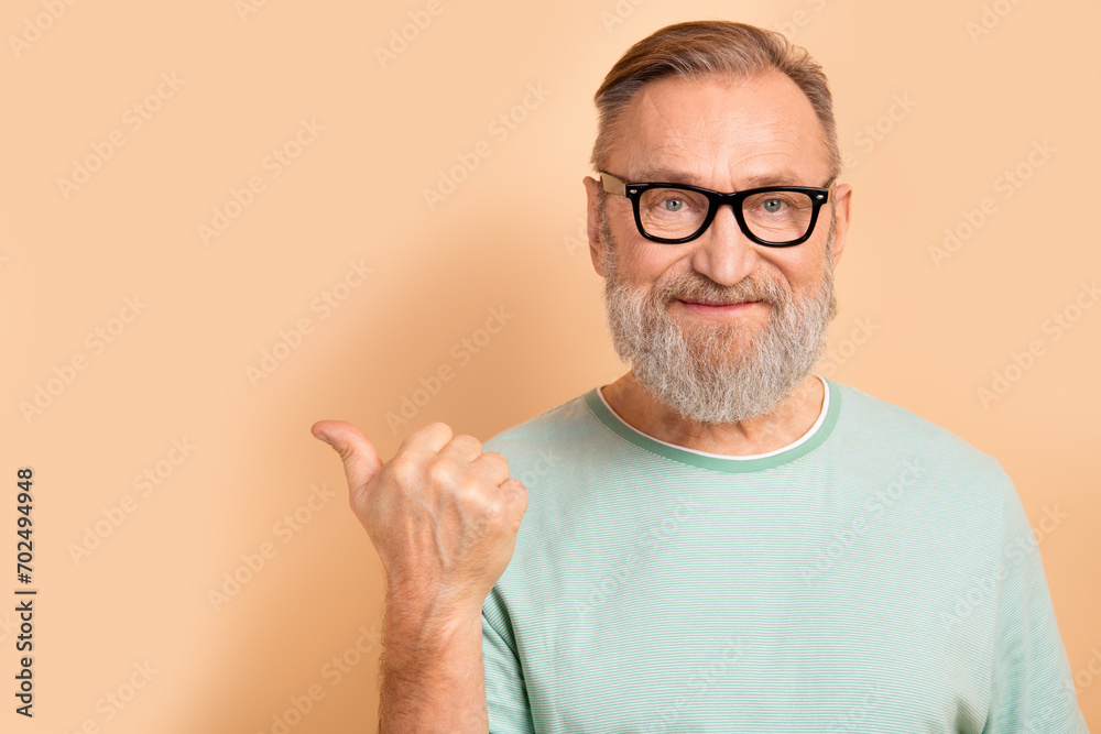 Portrait of pleasant smart senior man in glasses wear stylish t-shirt indicating at offer empty space isolated on pastel color background Portrait of pleasant smart senior man in glasses wear stylish t-shirt indicating at offer empty space isolated on pastel color background