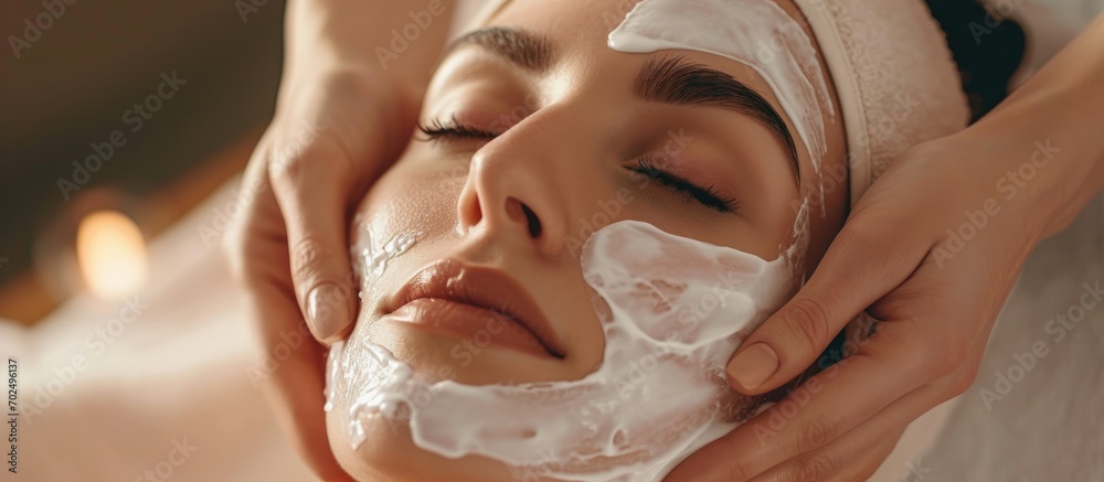 Beautician applying moisturizing mask to woman's face in skincare treatment. Beautician applying moisturizing mask to woman's face in skincare treatment.