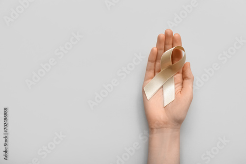 Woman with beige ribbon on light background. Uterine cancer awareness concept photo