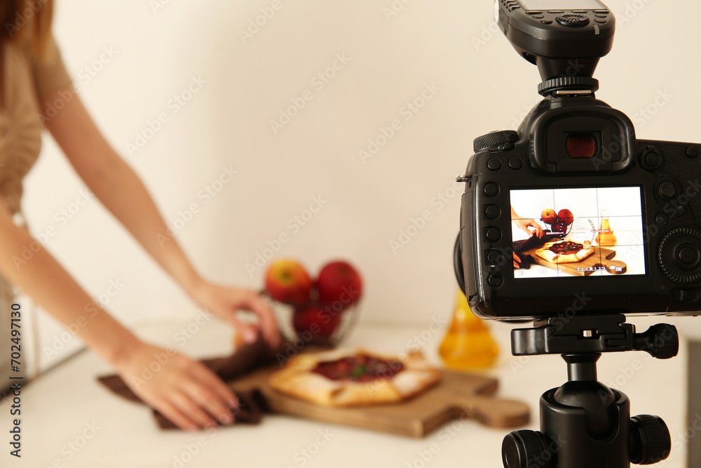 Woman making tasty apple pie on display of professional photo camera in studio - obrazy, fototapety, plakaty 