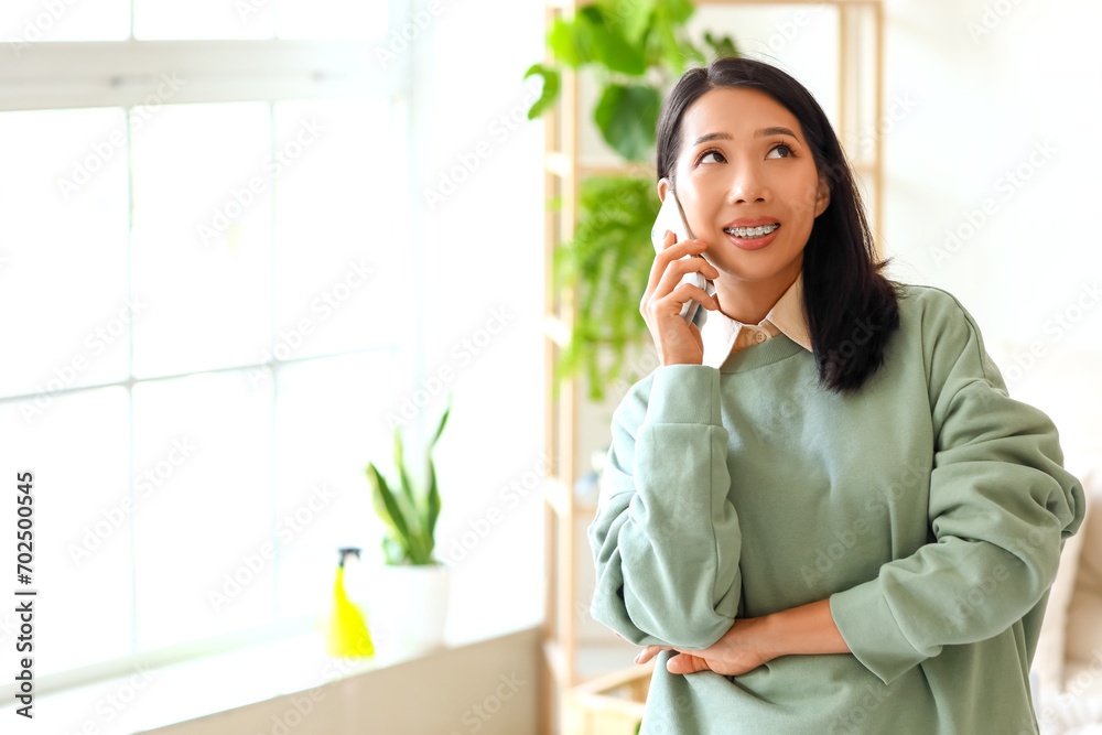 Young Asian woman talking by mobile phone at home Young Asian woman talking by mobile phone at home