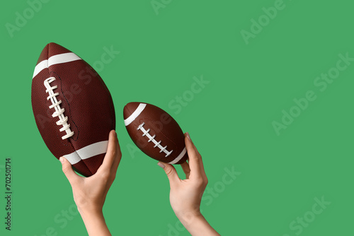 Female hands with balls for American football on green background photo