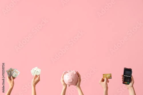Female hands with piggy bank, payment terminal, credit card and money on pink background