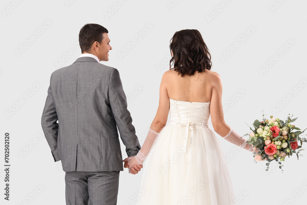 Young wedding couple with bouquet of flowers on white background, back view