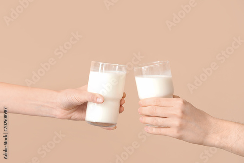 Hands holding glasses of milk on beige background
