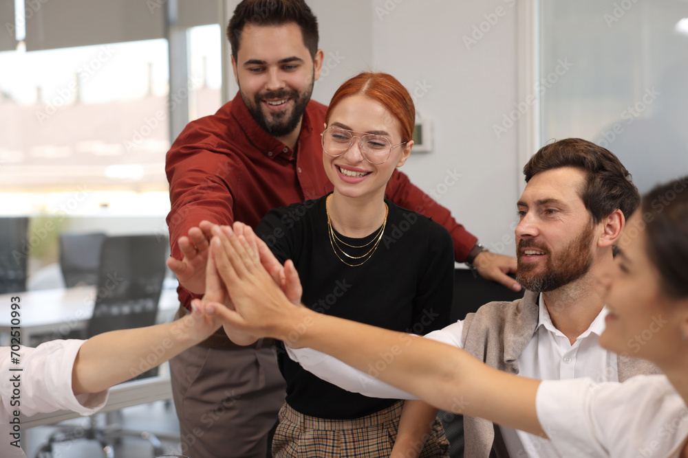 Team of employees joining hands in office Team of employees joining hands in office