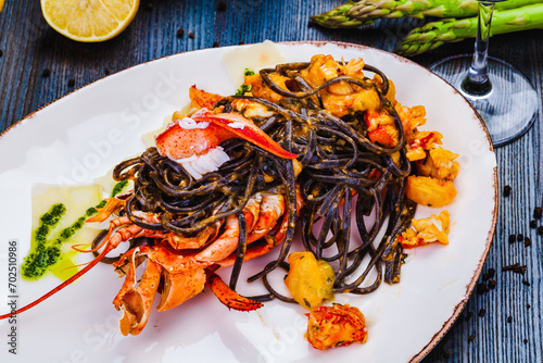 Squid ink tagliolini with lobster on white plate