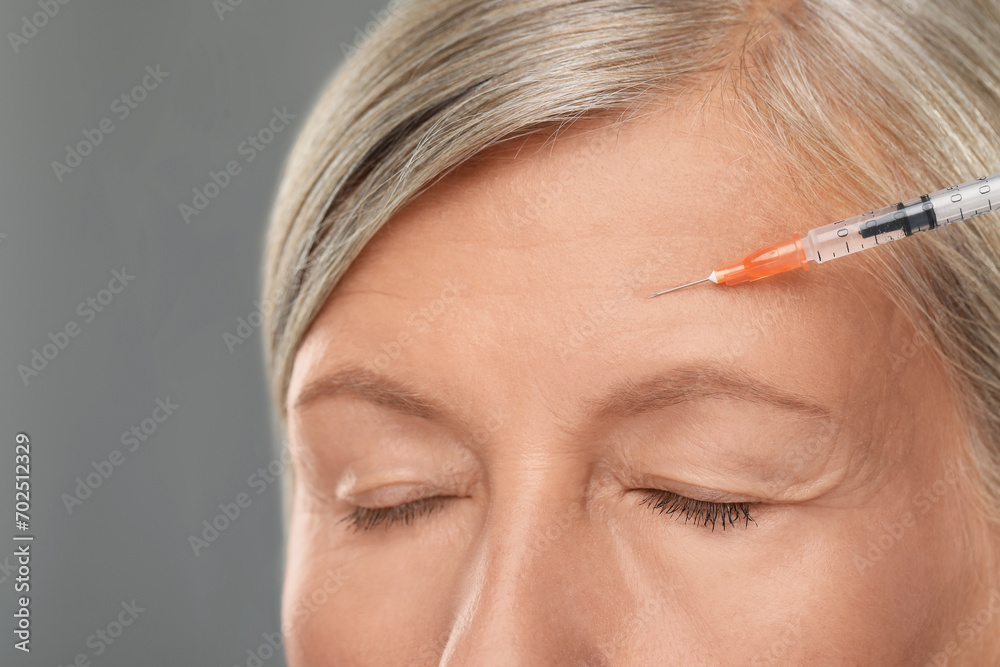 Senior woman getting facial injection on light grey background, closeup. Cosmetic surgery Senior woman getting facial injection on light grey background, closeup. Cosmetic surgery