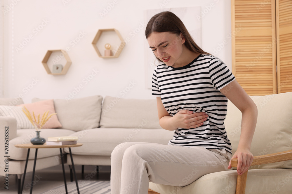 Young woman suffering from stomach pain at home. Space for text Young woman suffering from stomach pain at home. Space for text